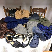 Photo showing the entire clothing and footwear lot, including ladies high heels, blue rubber crocs, kid's snow boots, various blazers, dresses, and coats.