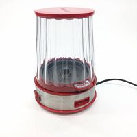 Side view of the Cuisinart EasyPop Popcorn Maker with clear plastic container and red lid sitting on a stainless steel base with red trim and power switch, showing the item from a slight angle.