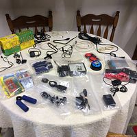 View of entire lot showing multiple cables, chargers, board game, and networking device on a table