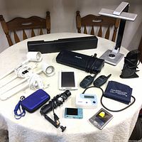 Overview of lot contents showing all electronics and accessories on white round table