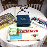 Full lot on table showing vintage Monopoly, two Trivial Pursuit games, Mario Lemieux NHL puzzle, and Skylanders Giants puzzle in original packaging.