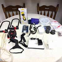 Full overview of the lot on table showing bike locks, pet clippers, straps, router, dryer caps, and other small items