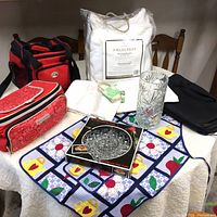 Full lot overview showing all items on table including cooler bags, white mattress cover bag, cut glass vase, hors d'oeuvre platter box, and Suisse watch bag