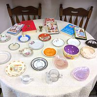 Overview photo showing all items on a table including plates, bowls, books, and DVDs for context and completeness.