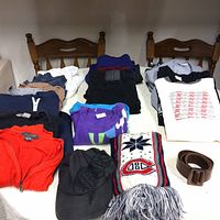 Full lot of clothing items spread on table including jacket, scarves, belt, and various shirts and pants.