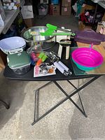 Full table view showing all kitchenware items laid out clearly: steamer, bowls, tongs, chopper, spring pans, cutting boards, and assorted small tools.