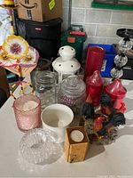 Photo showing various candles and candle holders including rooster-themed holders, glass, ceramic, and metal lantern.