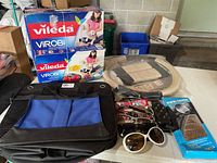 Photo showing two boxes of Vileda Virobi robot sweeper refills, trunk organizer bag, sunglasses, shoe spikes box, and more