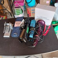 Photo of hair crimper, flat iron, curling iron, curling iron holder, and caddy mirror box grouped on table.