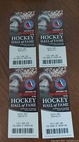 Four Hockey Hall of Fame tickets arranged side by side on a wooden surface showing front with logos and expiry details visible.