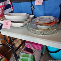 Photo taken showing the full assortment of serving platters and plates stacked beside each other on white folding table.