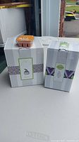 Two boxed Scentsy products placed on a table next to a single wax bar pack with six segments on top of one box. Boxes display the white wax warmer packaging and the wax melt packaging.