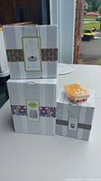 Three boxed items: Scentsy wax warmer, warm wrap, and wax bar with a visible orange wax clamshell on top