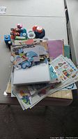 Pile of assorted scrapbooking papers, stickers, and cut-out embellishments including Creative Memories 12x12 pages