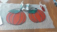 Two stained glass pumpkins, two night light bases, and a stained glass flip flop ornament on bubble wrap