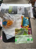 Photo showing flexible water containers with white caps and colored spouts (blue and orange), reusable sandwich/snack bags with green clips.
