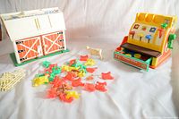 Photo showing both Fisher Price vintage toys side by side on white background: Family Barnyard with farm animals and Family Cash Register with open coin drawer