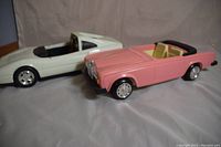 White Ferrari 308 GTSi Barbie car and pink Rolls Royce Barbie car side by side on white background, showing overall shape, missing parts noted