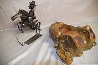 Photo showing both the metal sculpture of a man on horseback and the wood carved wine holder placed side by side.