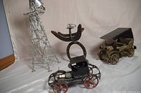 Four handmade metal art pieces displayed together: barbed wire windmill, horseshoe man, and two Model T trucks.