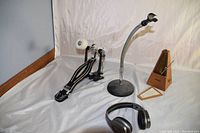 Photo showing all 4 items: metronome, wireless headphones, microphone stand, and bass drum pedal.