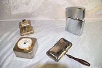 All four vintage metal items: lighter, clock, crumb cleaner, and decorative box together