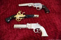 Three vintage Avon perfume bottles shaped like guns, displayed on red velvet fabric. Each bottle holds liquid perfume and features distinctive design details.