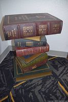 Front view showing the stacked faux books with decorative titles and embossed gold detailing.