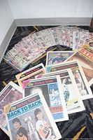 Photo showing a large spread of hockey cards in protective sleeves arranged in a fan with several vintage Hockey News magazines laid out in front.