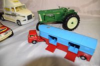 Photo showing a green Oliver tractor, white Tiara Yachts truck, red rescue SUV, and blue horse trailer attached to a small red cab