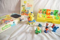 Photo showing Sesame Street 1985 board game box, 1971 story book, Big Bird train car, character figures, and Playskool toy with seats and figures