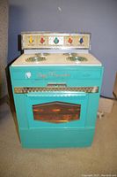 Front view of vintage Suzy Homemaker child's toy oven showing control panel, stovetop coils, and oven door with transparent window.