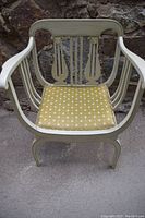 Front view showing carved lyre design on backrest and fitted yellow floral cushion on seat.
