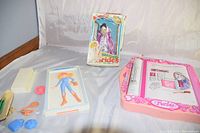 Photo of Barbie drawing board, Ginny International Bride doll in box, and various Barbie fashion accessories spread on fabric