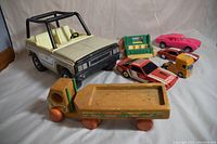 Photo of all vintage toy vehicles in the lot showing a large cream Tonka Jeep, two pink/red Camaro cars, a wooden flatbed truck, yellow semi cab, red and white Pro Max RC car without remote, and Fisher Price camper truck body.