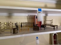 Shelf with seven miniature dollhouse bedroom furniture pieces mostly metal, including beds, chests and tables