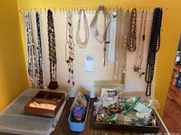 Hanging necklaces on pegboard and boxes of jewelry below