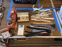 Lot overview showing watches, bands, rings, clock, and packaging box on table.