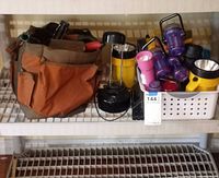 Full view of the lot showing various flashlights in multiple colors, a black lantern, and a brown garden tool bag