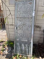 Full view of the leaded glass door standing outdoors showing metal frame and overall design