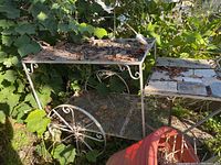 Full view of weathered metal bar cart outdoors surrounded by vegetation