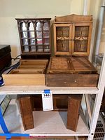 Front view of four mini wooden cabinets arranged on a shelf showing details of doors and compartments