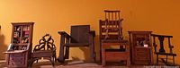 Photo showing the full set of five miniature chairs and two secretary furniture pieces with bookcases against a yellow background.