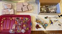 Overview of miniature doll house accessories including multiple small packaged items and loose items on a surface.