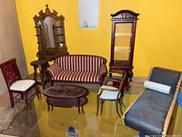 Photo shows nine miniature Victorian/Edwardian furniture pieces arranged on a glass surface against a yellow background. Includes loveseat, chaise lounge, chairs, cabinet, coffee table, and vanity.
