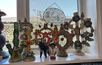 All items displayed on windowsill: six ceramic candle holders and two visible folk figures