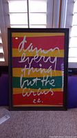 Front view of framed wall art with colorful horizontal stripes and white cursive text.