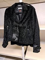 Full front view of textured black faux fur Adrienne Vittadini coat with crocodile-style leather panels and toggle closure