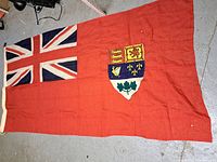 Full view of red field, Union Jack canton and central coat of arms.