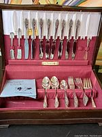 Complete set of Community flatware arranged neatly inside its vintage wooden case with red fabric lining.
